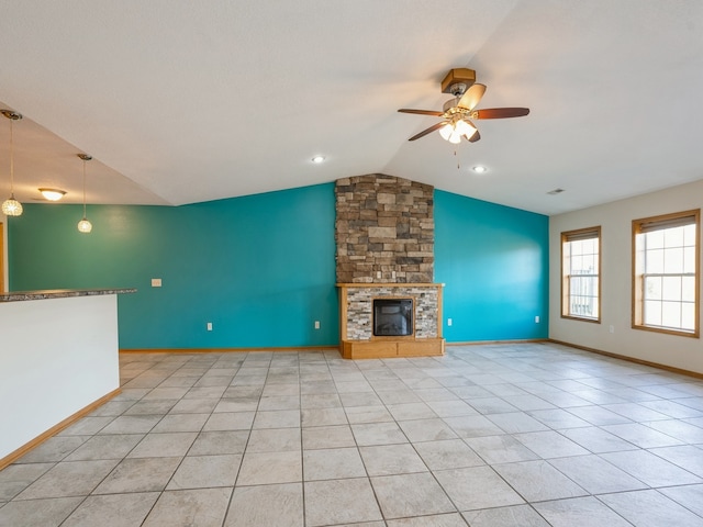 unfurnished living room featuring a stone fireplace, light tile patterned flooring, vaulted ceiling, and ceiling fan