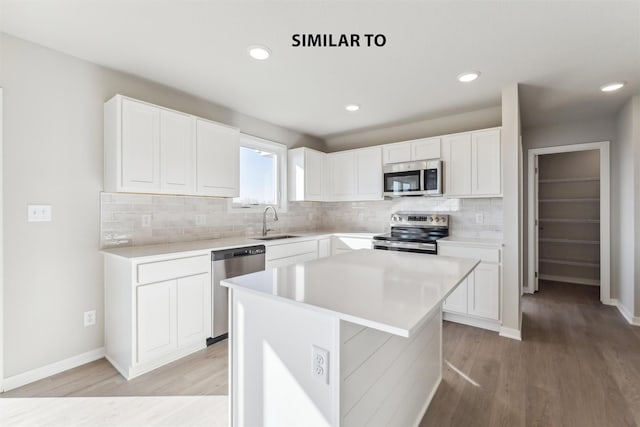 kitchen featuring appliances with stainless steel finishes, light hardwood / wood-style floors, a center island, sink, and white cabinetry