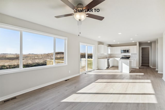 unfurnished living room featuring a healthy amount of sunlight, ceiling fan, light hardwood / wood-style flooring, and sink