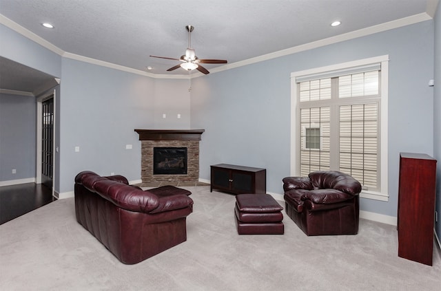 carpeted living room featuring ceiling fan, a textured ceiling, ornamental molding, and a fireplace