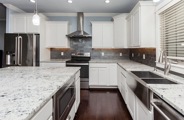 kitchen featuring stainless steel appliances, white cabinetry, wall chimney exhaust hood, hanging light fixtures, and dark hardwood / wood-style flooring