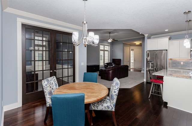 dining room with dark hardwood / wood-style flooring, a textured ceiling, ornamental molding, and ceiling fan with notable chandelier