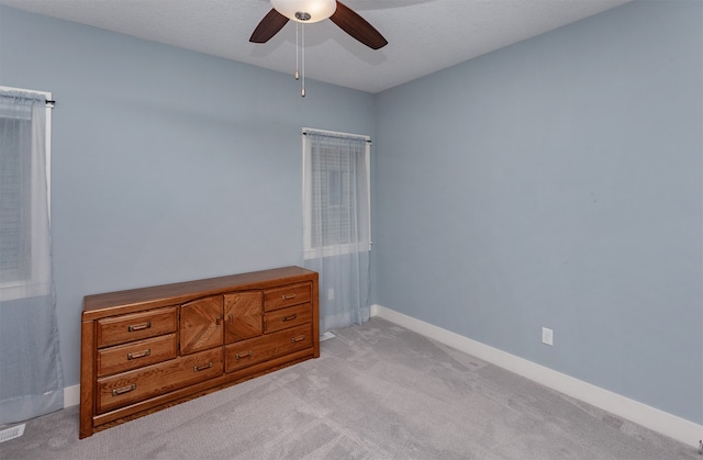 unfurnished bedroom with a textured ceiling, light carpet, and ceiling fan