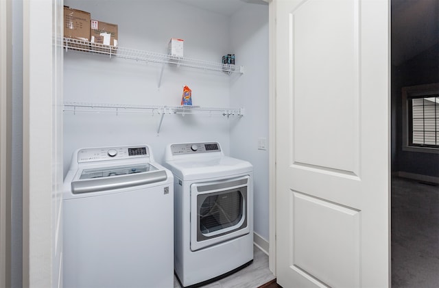 clothes washing area with washer and clothes dryer and light hardwood / wood-style floors