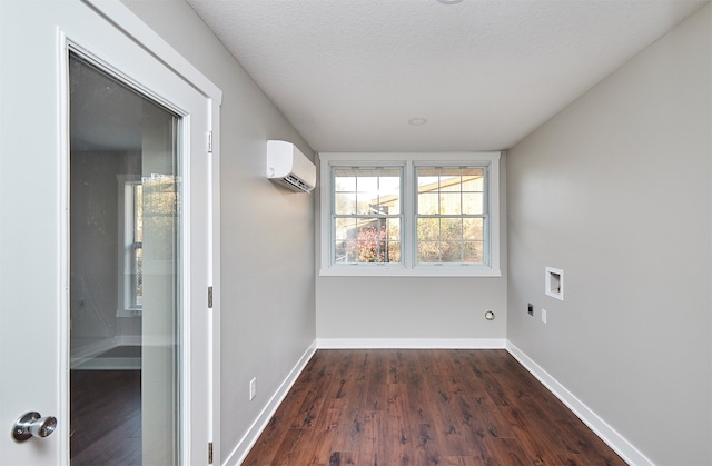 empty room with a textured ceiling, an AC wall unit, and dark wood-type flooring