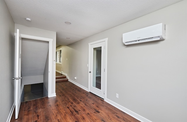 unfurnished bedroom featuring a wall mounted AC, dark wood-type flooring, and a textured ceiling