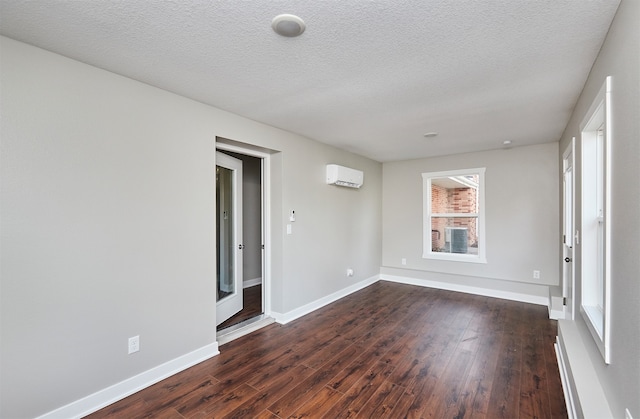 unfurnished room with a wall mounted air conditioner, dark hardwood / wood-style floors, and a textured ceiling