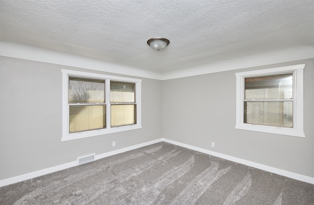 carpeted empty room featuring a textured ceiling