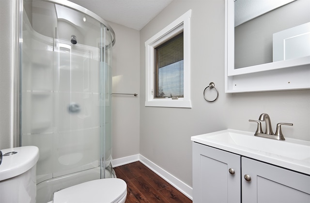 bathroom featuring hardwood / wood-style floors, vanity, toilet, and a shower with door