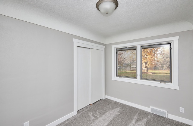 unfurnished bedroom with carpet flooring, a textured ceiling, and a closet