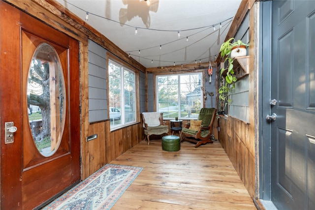 foyer with light wood-type flooring and wood walls