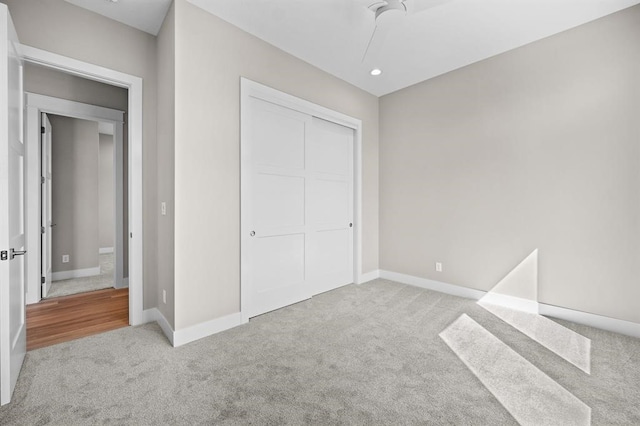 unfurnished bedroom with light carpet, ceiling fan, and a closet