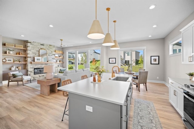 kitchen with white cabinets, hanging light fixtures, sink, and a kitchen island with sink