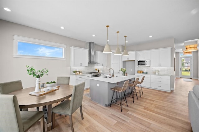 kitchen featuring white cabinets, wall chimney exhaust hood, and a healthy amount of sunlight