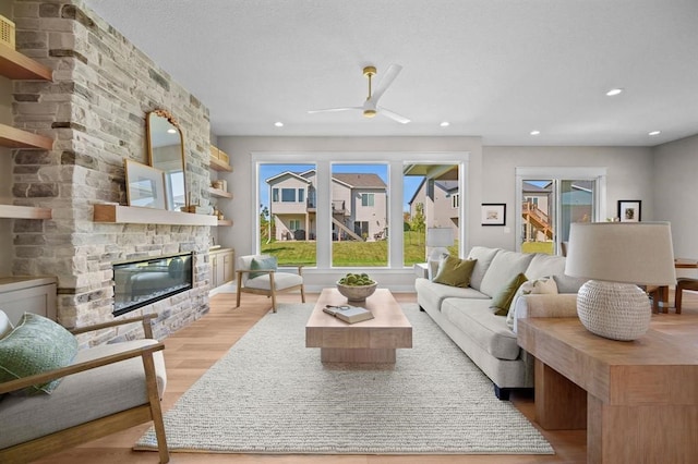 living room with a fireplace, ceiling fan, and light hardwood / wood-style flooring