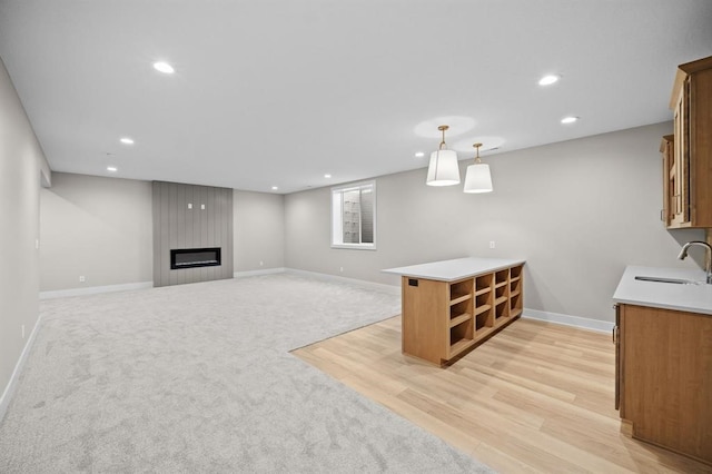 basement featuring light wood-type flooring, sink, and a large fireplace