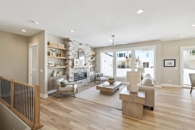 living area featuring a large fireplace, light wood finished floors, a textured ceiling, and recessed lighting