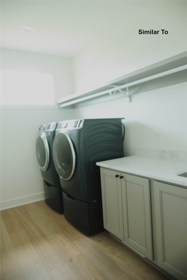 laundry area featuring cabinets, light hardwood / wood-style floors, and independent washer and dryer