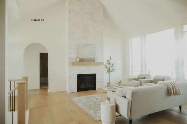 living room with high vaulted ceiling, light hardwood / wood-style floors, and a fireplace