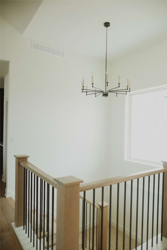 staircase with hardwood / wood-style flooring and a notable chandelier