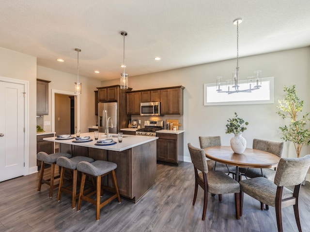 kitchen with appliances with stainless steel finishes, dark hardwood / wood-style floors, and decorative light fixtures