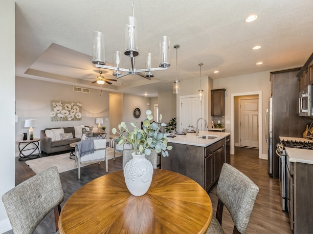 dining area with a textured ceiling, dark wood-type flooring, sink, and ceiling fan