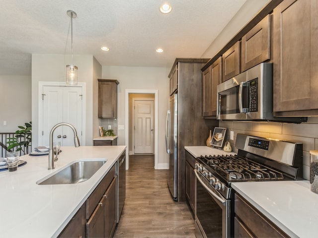 kitchen with appliances with stainless steel finishes, a textured ceiling, dark hardwood / wood-style floors, pendant lighting, and sink