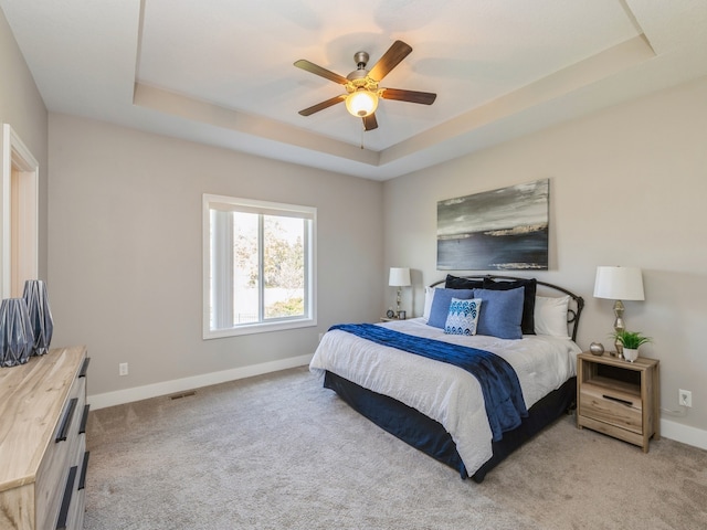 bedroom with light colored carpet, ceiling fan, and a raised ceiling