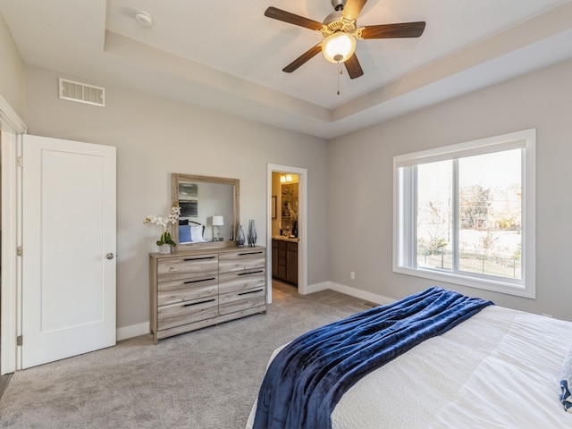 carpeted bedroom with ceiling fan, a tray ceiling, and connected bathroom