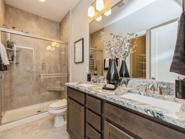 bathroom with a shower with shower door, vanity, and toilet