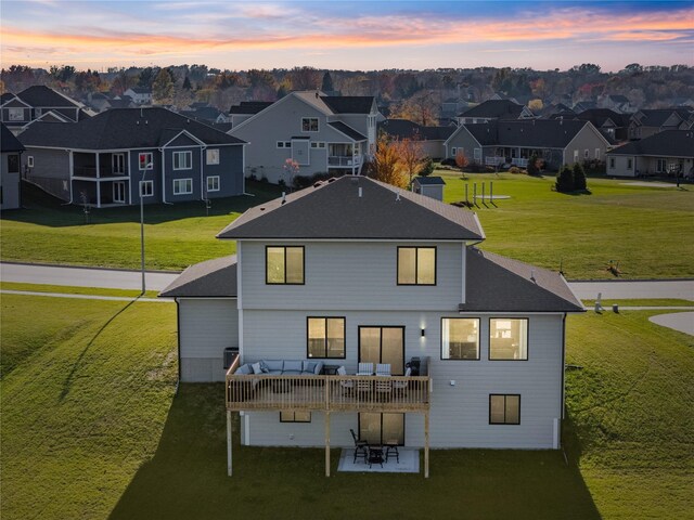 back house at dusk with outdoor lounge area and a yard