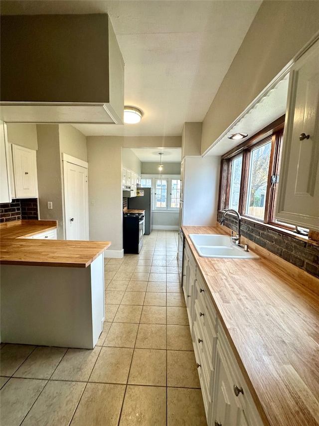 kitchen with white cabinets, wood counters, a healthy amount of sunlight, and sink