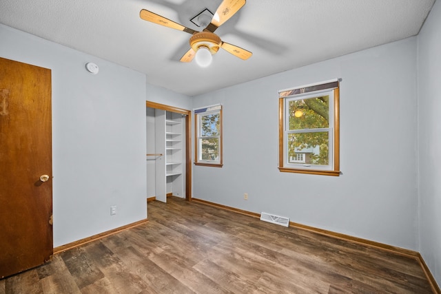 unfurnished bedroom featuring ceiling fan, a closet, dark wood-type flooring, and a textured ceiling