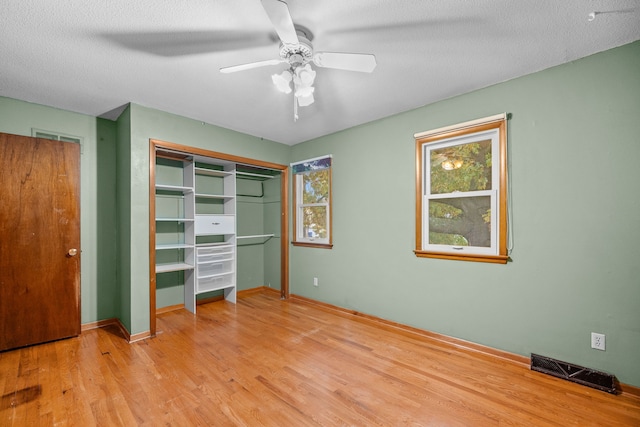 unfurnished bedroom featuring multiple windows, a textured ceiling, light hardwood / wood-style floors, and ceiling fan