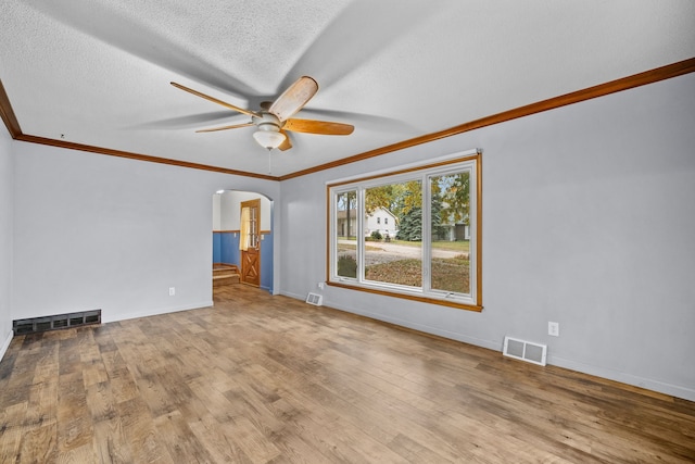 unfurnished room featuring ceiling fan, light wood-type flooring, a textured ceiling, and ornamental molding