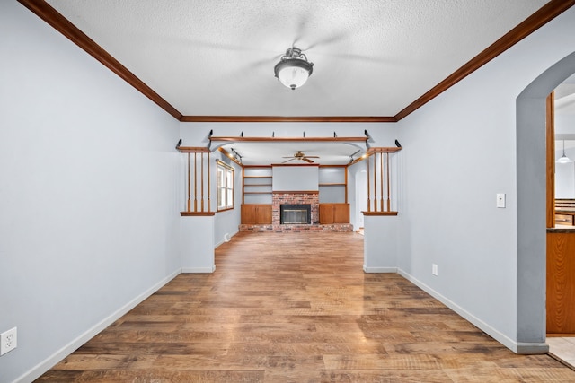 interior space with ceiling fan, light hardwood / wood-style floors, a textured ceiling, and a brick fireplace