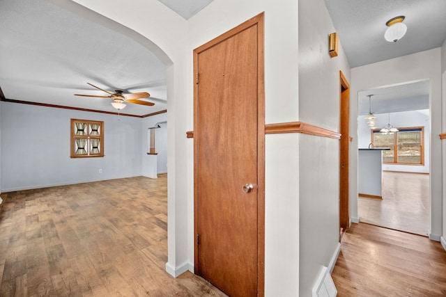 hall with a textured ceiling, light hardwood / wood-style floors, an inviting chandelier, and crown molding