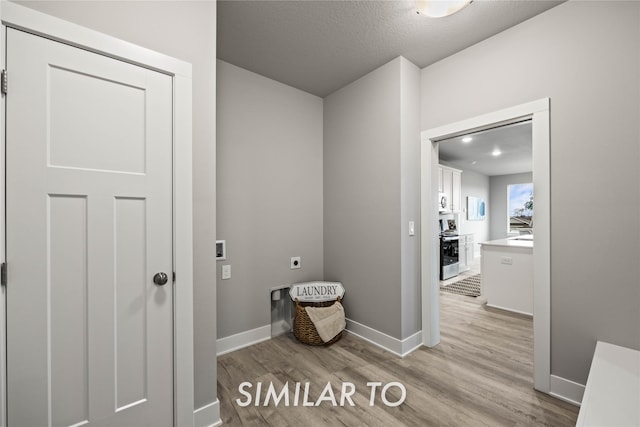 interior space featuring electric dryer hookup, washer hookup, a textured ceiling, and light wood-type flooring