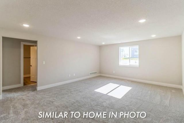 unfurnished room with light carpet and a textured ceiling