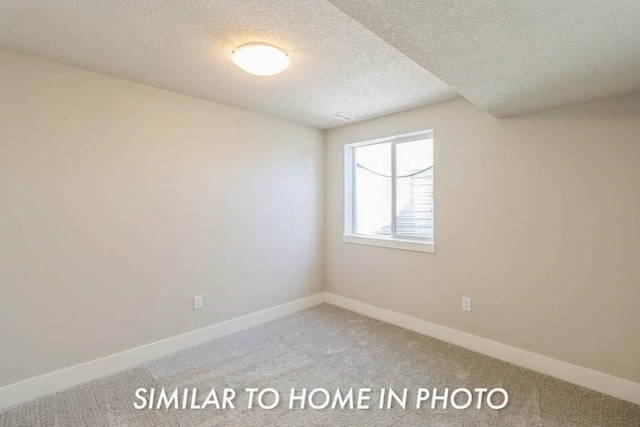 unfurnished room with light colored carpet and a textured ceiling