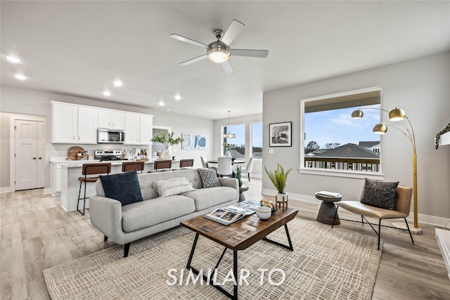 living room with light hardwood / wood-style flooring and ceiling fan