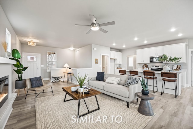 living room featuring ceiling fan and light hardwood / wood-style flooring