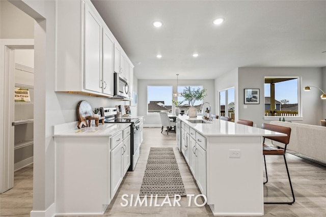 kitchen with stainless steel appliances, white cabinetry, hanging light fixtures, and sink