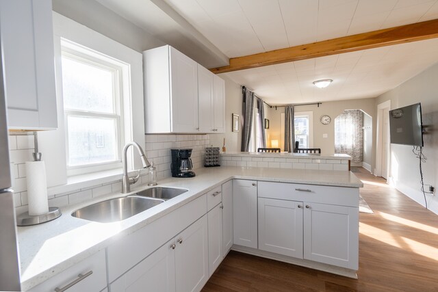 kitchen with white cabinets, dark wood-style flooring, beam ceiling, a sink, and decorative backsplash