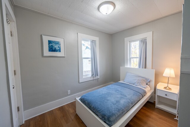 bedroom with baseboards, multiple windows, and dark wood-style flooring