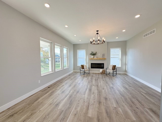 unfurnished living room featuring light wood-type flooring and a notable chandelier