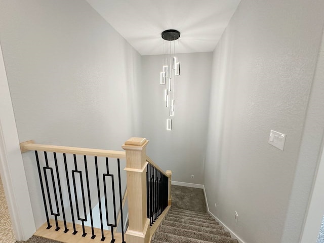 stairway with carpet flooring and a chandelier