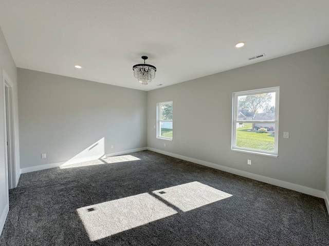 carpeted spare room featuring a wealth of natural light and a chandelier