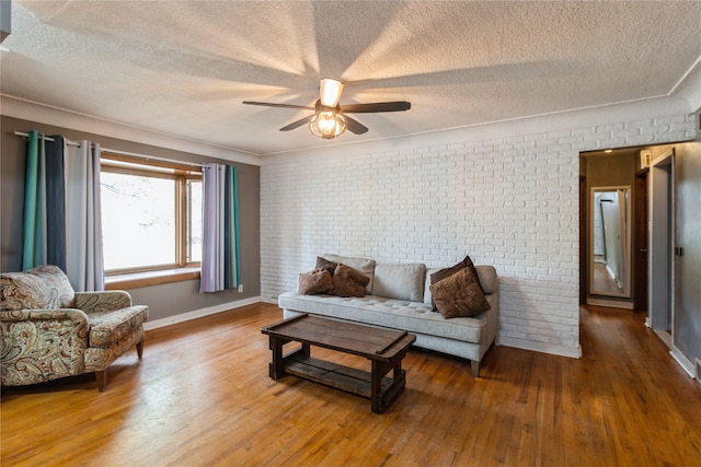 living room featuring brick wall, wood-type flooring, and a textured ceiling