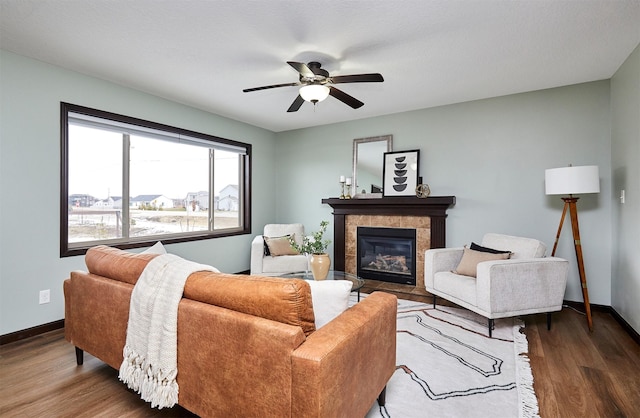 living room with dark hardwood / wood-style floors, ceiling fan, and a tiled fireplace